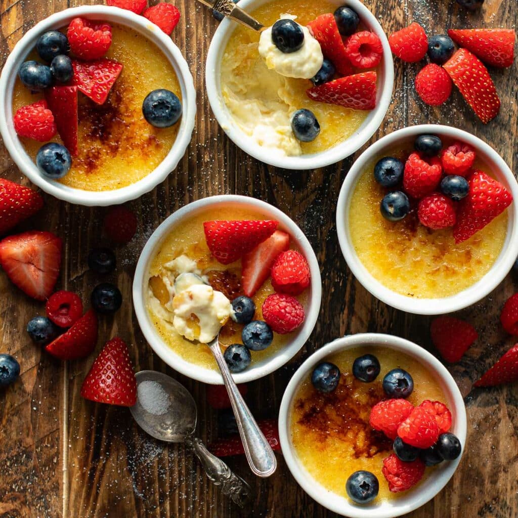 French creme brulee in white ramekins topped with fresh berries