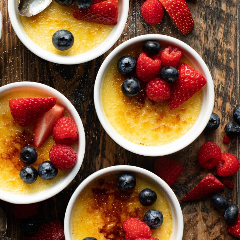 French recipe for vanilla creme brulee topped with fresh strawberries, blueberries and raspberries