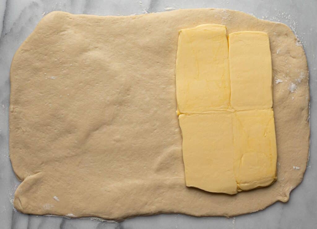 Pastry dough in a rectangle with butter blocks on half of it