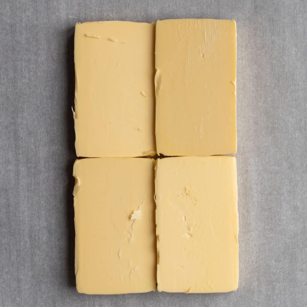 Four rectangular blocks of butter on a parchment sheet