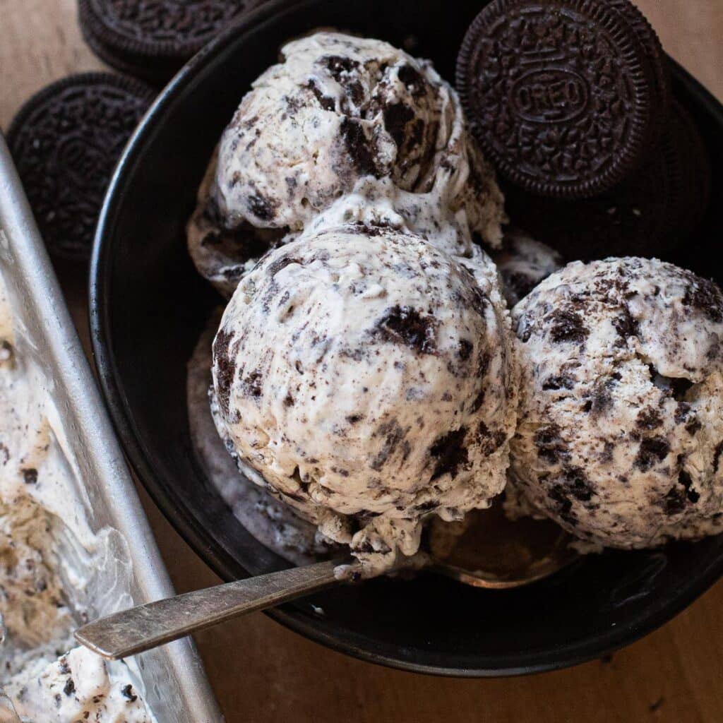 Three scoops of homemade Oreo ice cream in a black bowl