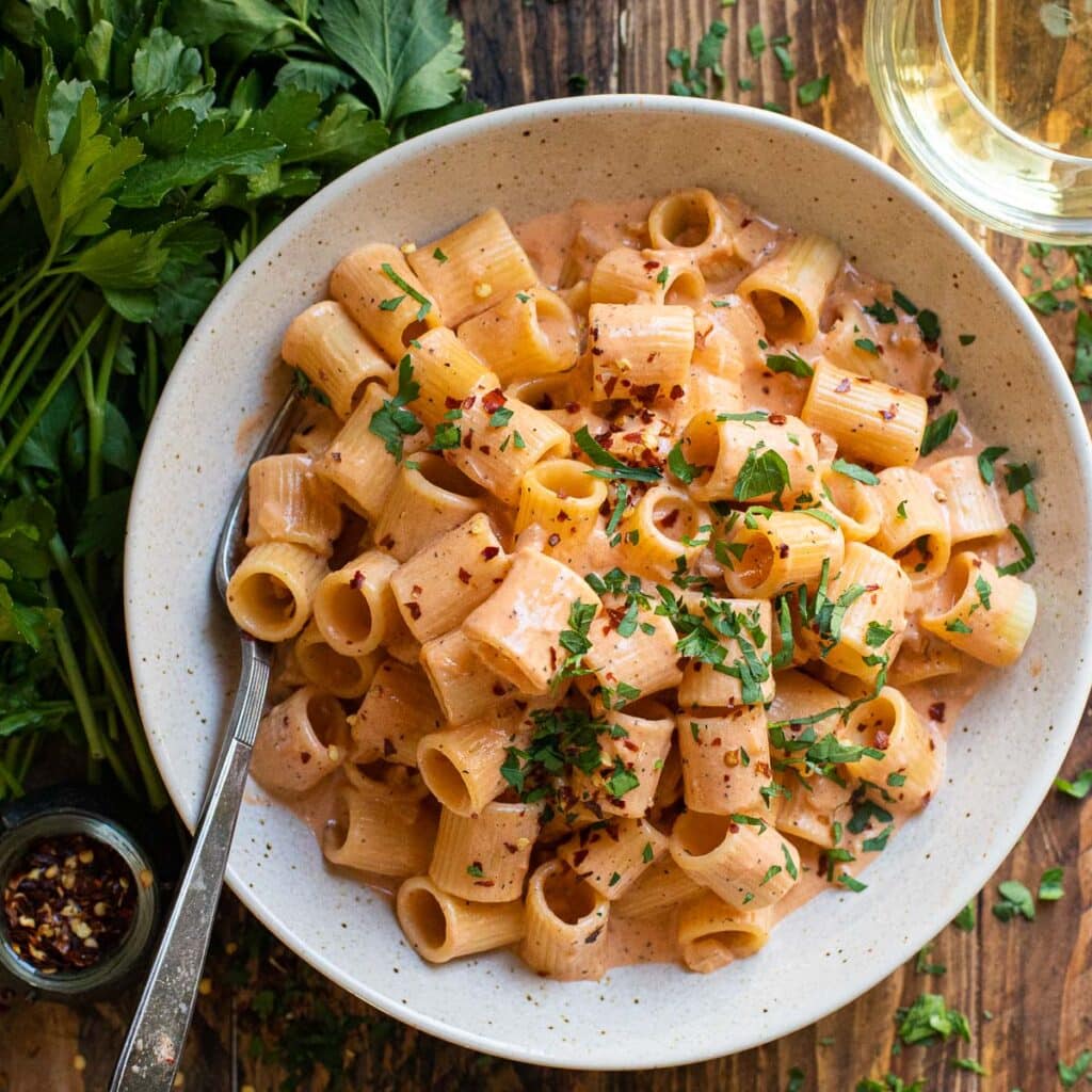 A bowl of pasta with blush sauce garnished with fresh parsley