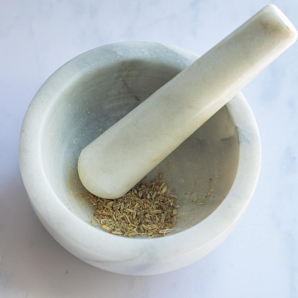 Fennel seeds in a marble mortar with a pestle
