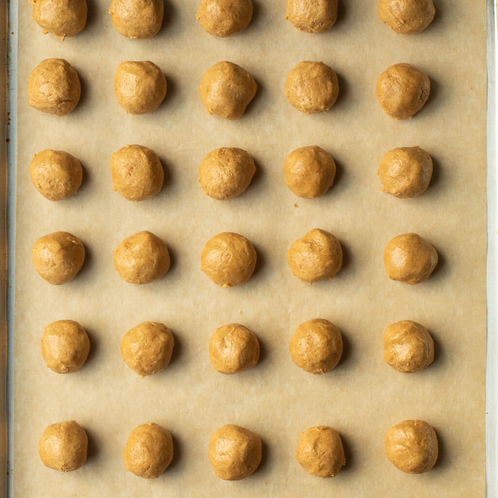 Peanut butter balls arranged in rows on a baking sheet