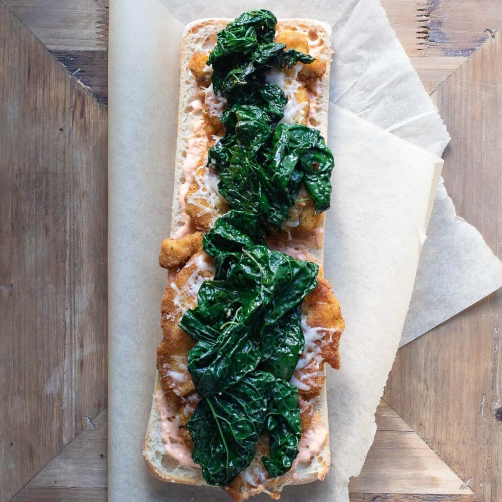 Tuscan kale on top of chicken cutlets on ciabatta bread