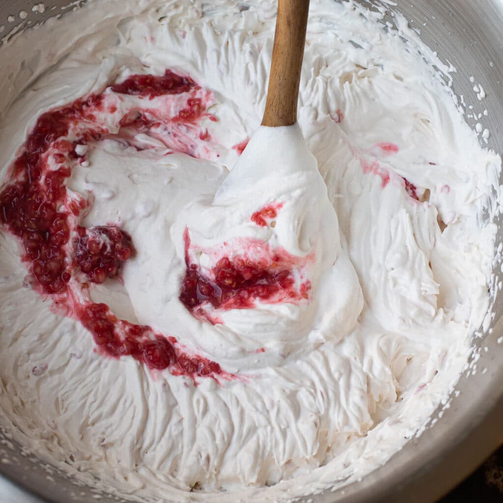 raspberry puree being mixed into whipped cream