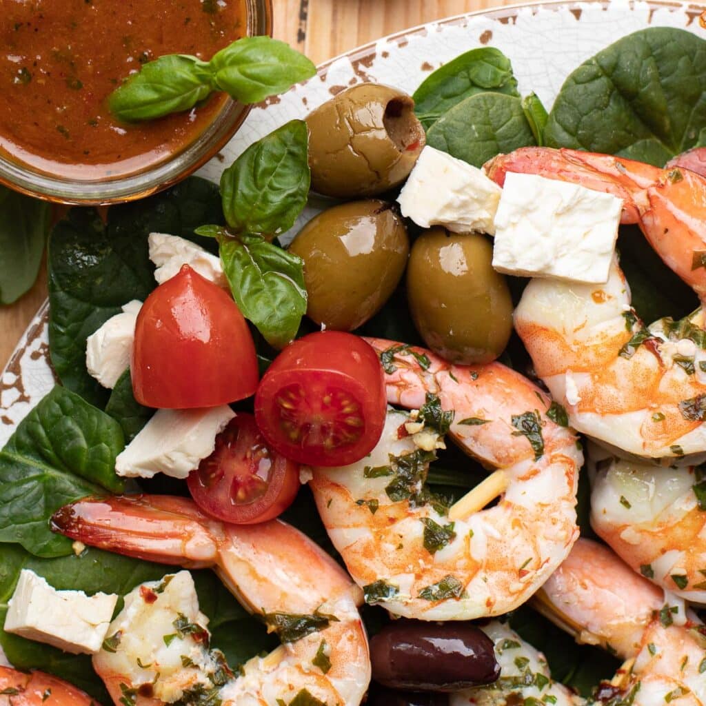 grilled shrimp, grape tomatoes, Greek olives and feta cheese on a bed of spinach