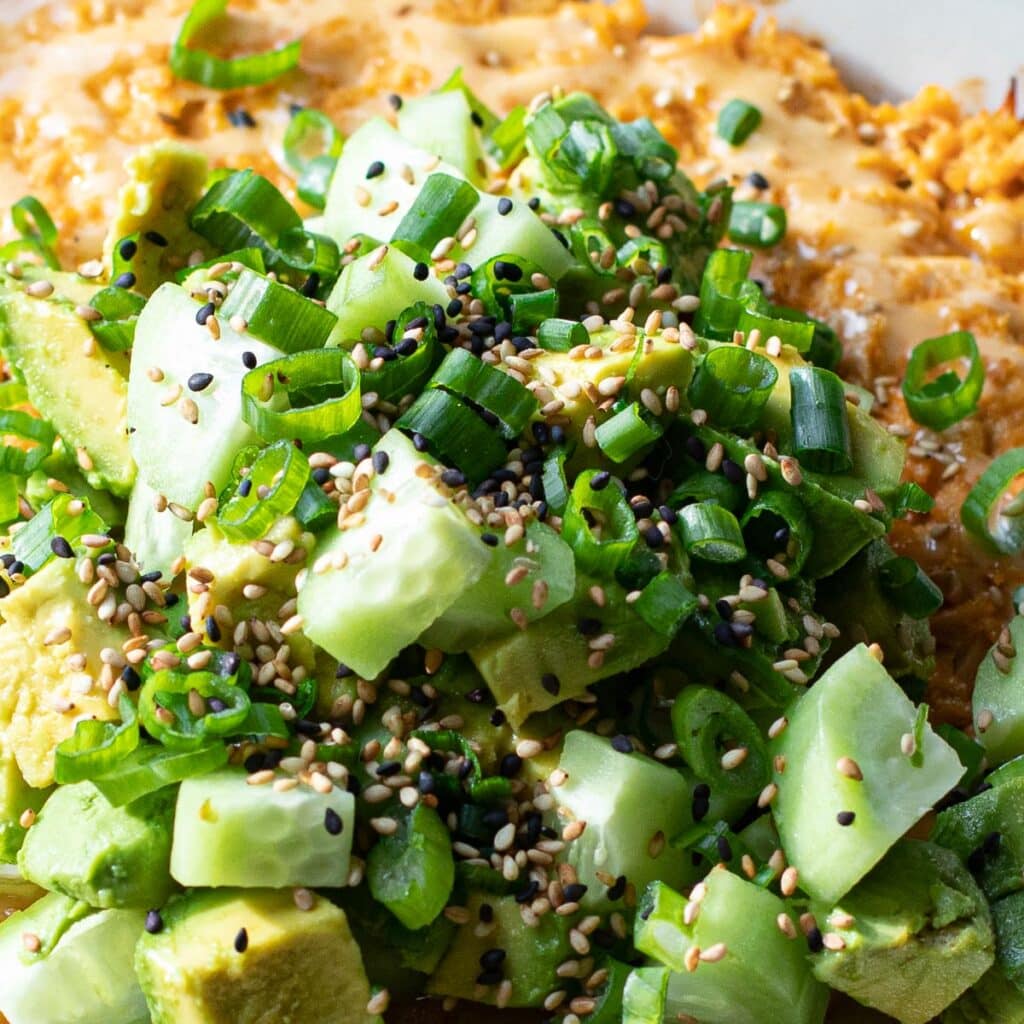 Scallions, sesame seeds and cucumbers on top of a sushi bake