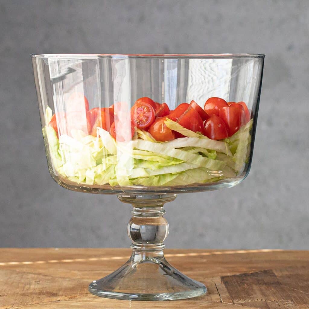 shredded lettuce and diced tomatoes in a trifle dish