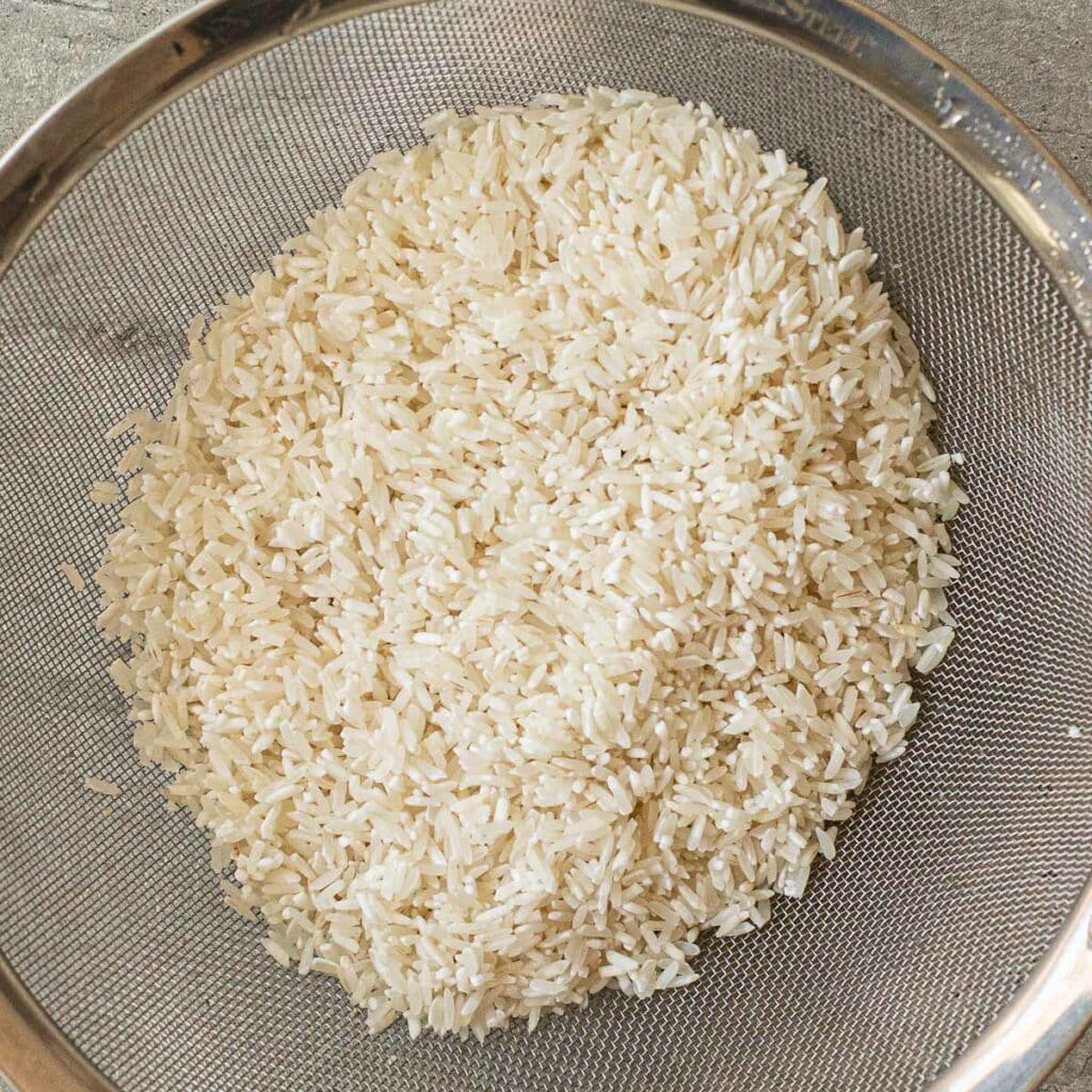 long grain rice in a wire mesh strainer
