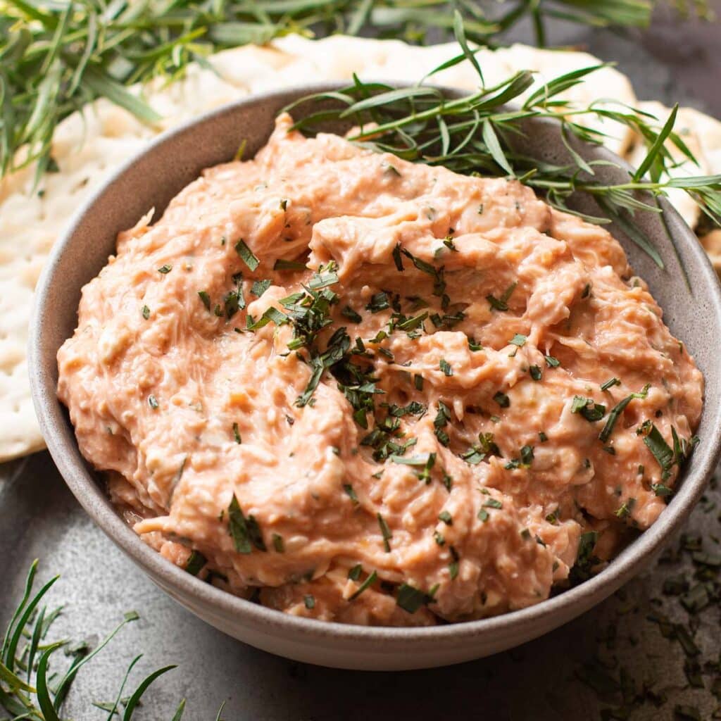 cold crab dip in a gray bowl topped with chopped tarragon