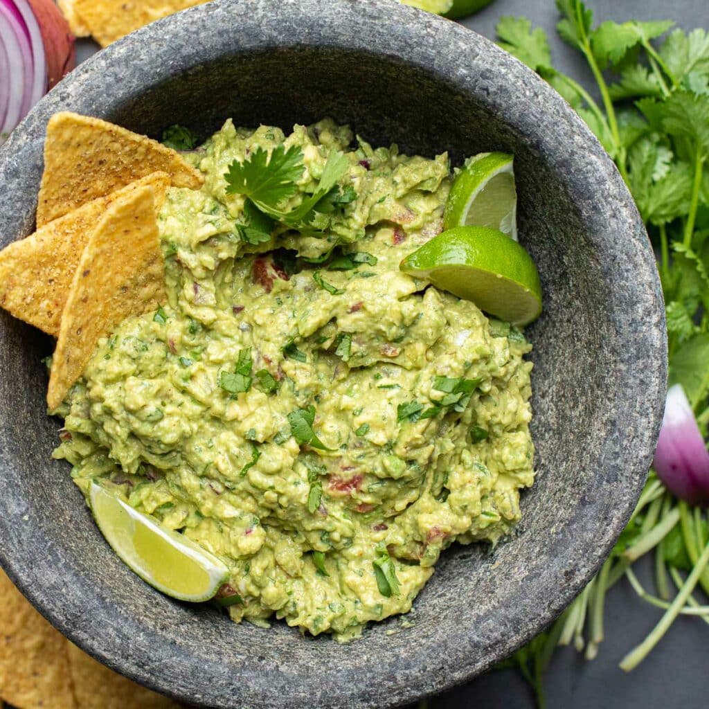best guacamole recipe in a gray molcajete with lime wedges