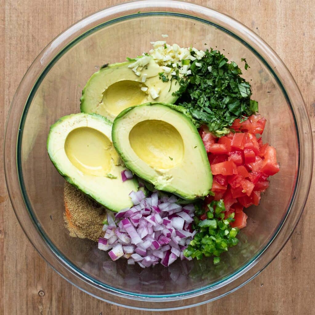 ingredients for guacamole chopped in a glass bowl