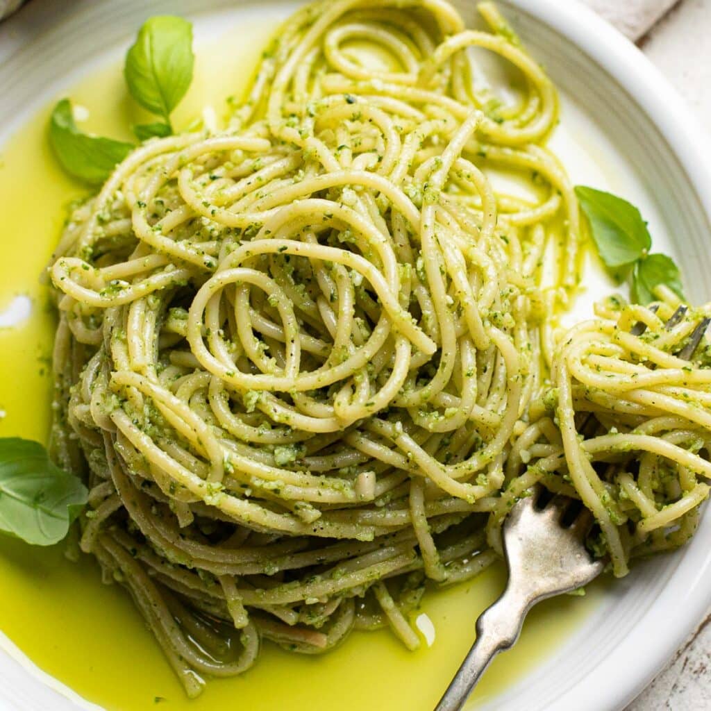pesto pasta on a white dish with a silver fork