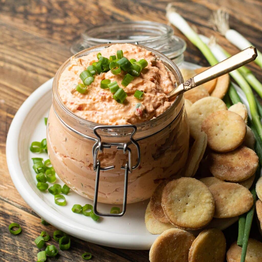 pimento cheese in a glass jar topped with chopped scallions