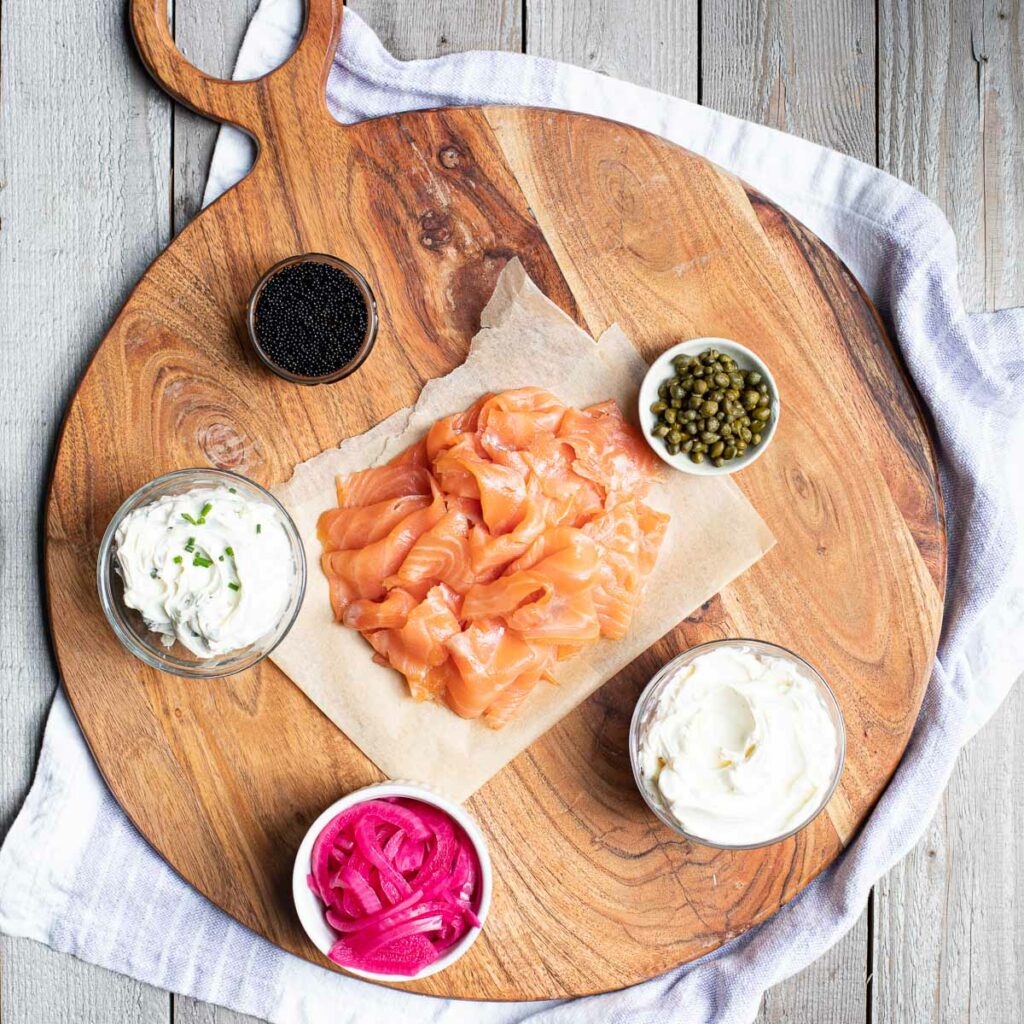 smoked salmon, cream cheese, pickled onions, capers and caviar positioned on a charcuterie board