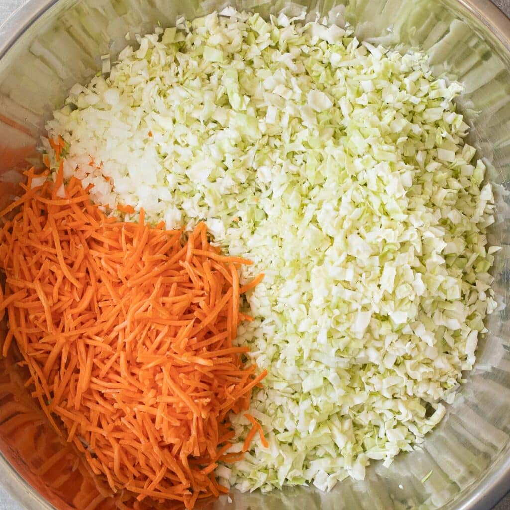 chopped green cabbage and matchstick carrots in a large mixing bowl
