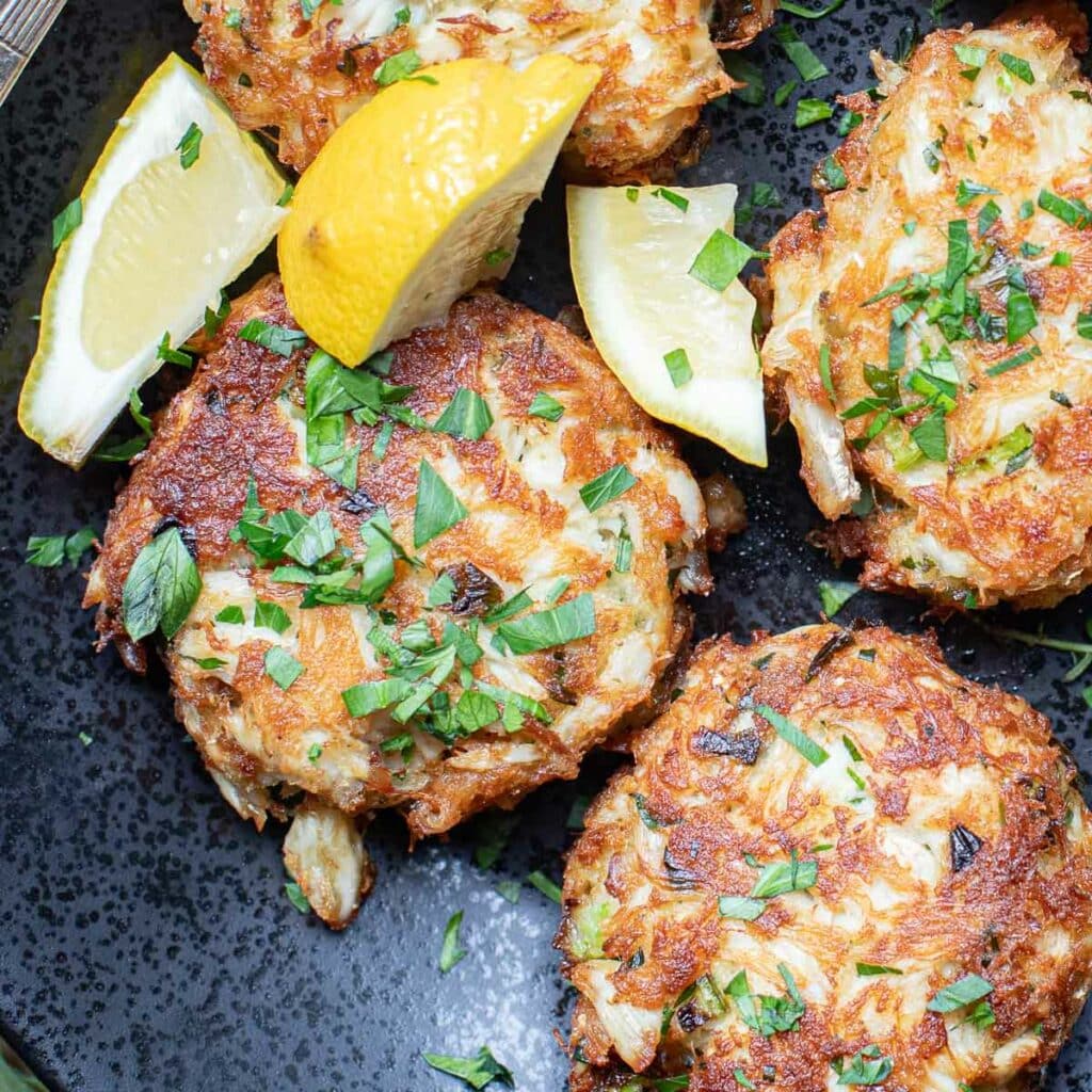 crab cakes garnished with fresh parsley and lemon wedges