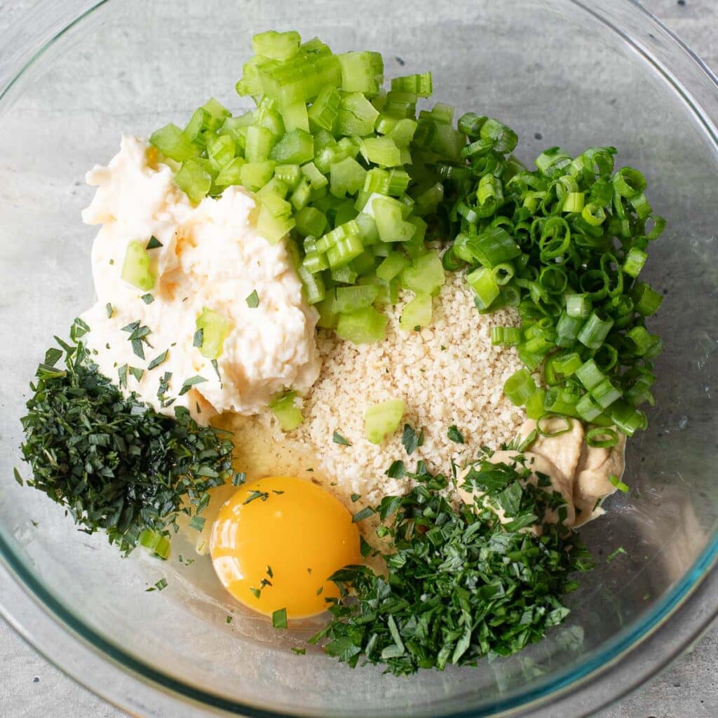 chopped herbs, scallions, one egg, bread crumbs and mayonnaise in a glass mixing bowl