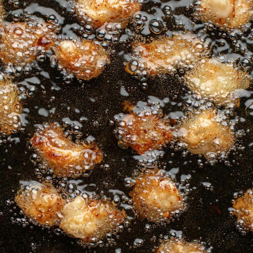 pieces of chicken frying in oil