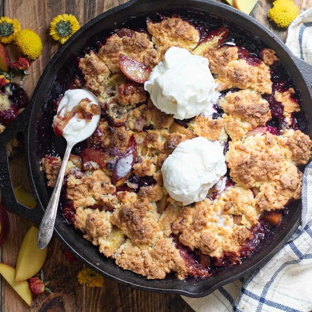 peach blueberry cobbler topped with scoops of vanilla ice cream
