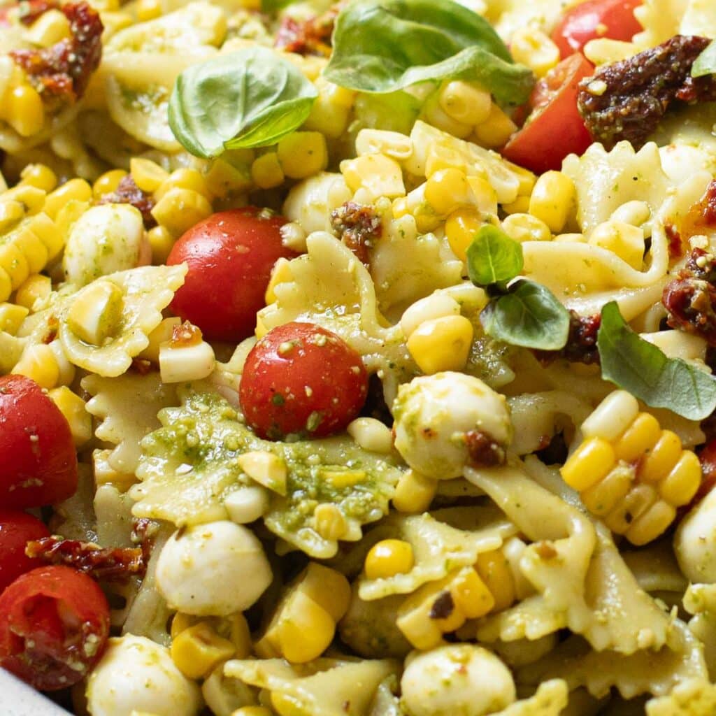 farfalle pasta salad with pesto sauce, corn, tomatoes and fresh basil