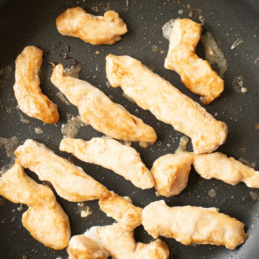sliced chicken breast cooking in a pan