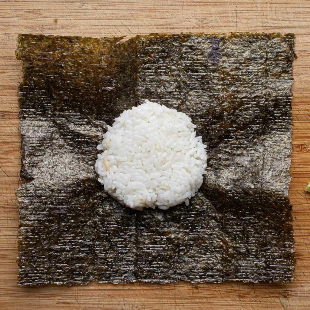 a sphere of sushi rice in the center of a nori sheet