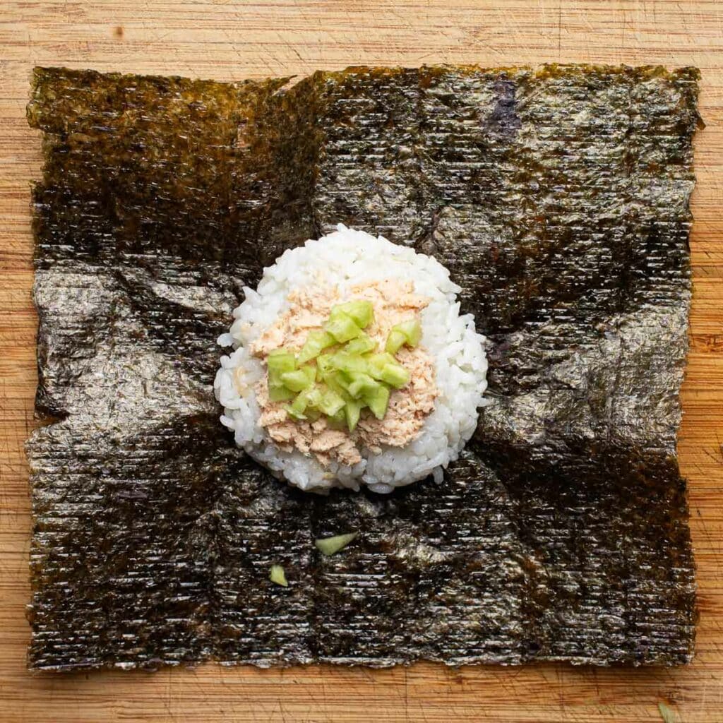 rice, spicy tuna mayo and chopped cucumbers on a sheet of nori