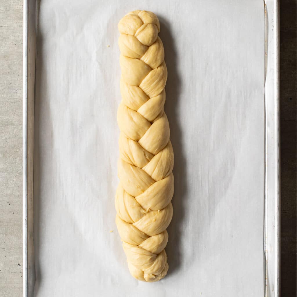 braided challah loaf before it is baked