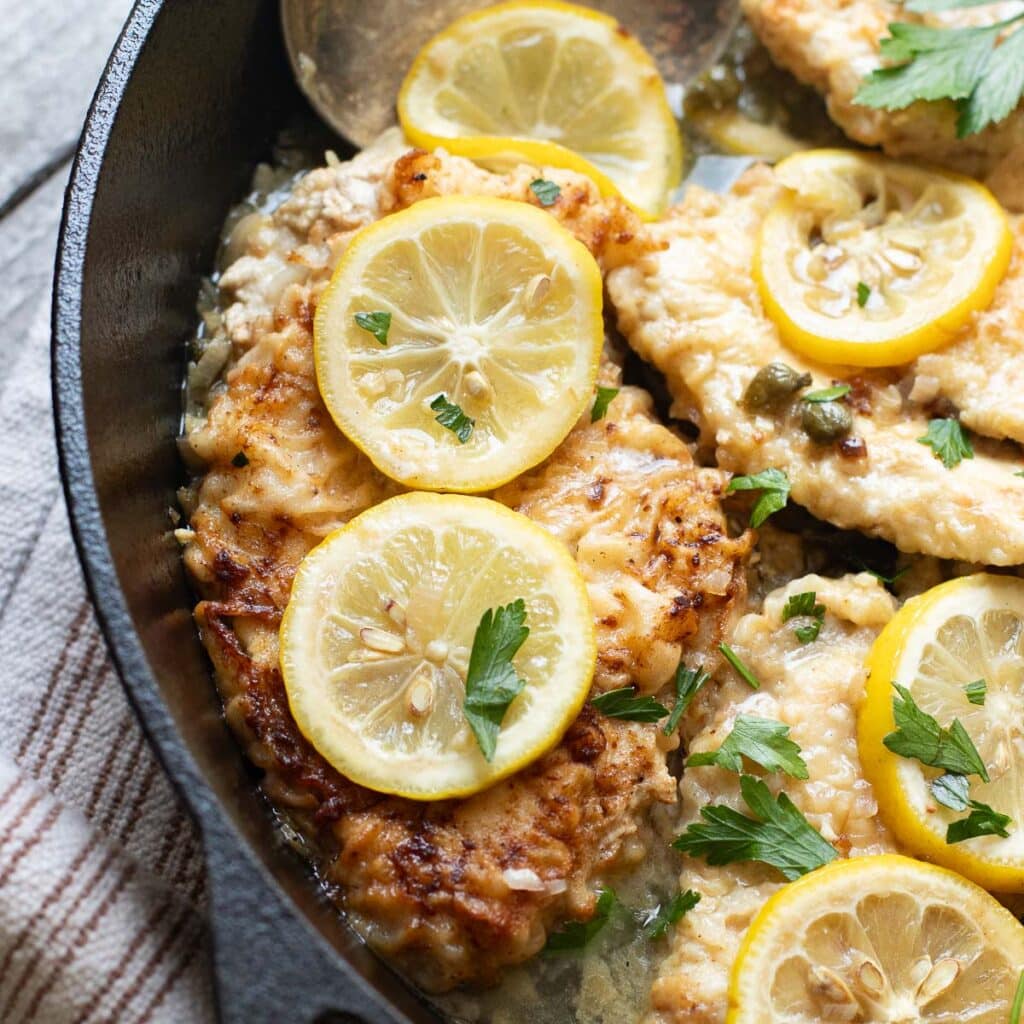 chicken piccata topped with lemon slices and parsley