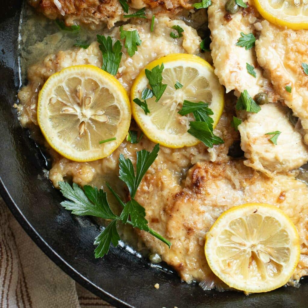 chicken piccata topped with fresh parsley and lemons