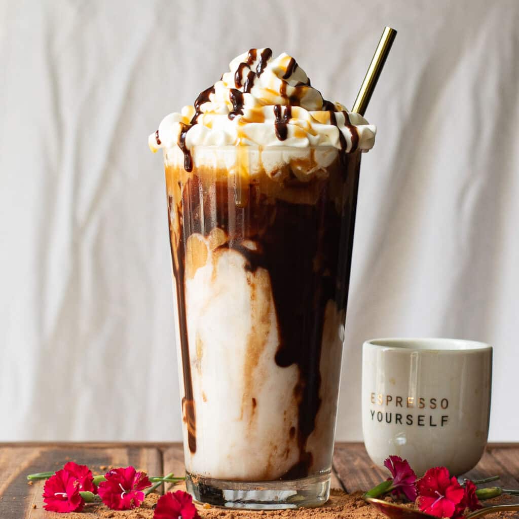 iced mocha macchiato in a tall glass topped with whipped cream