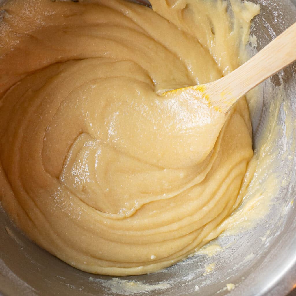 apple cake batter in a mixing bowl with a wooden spoon