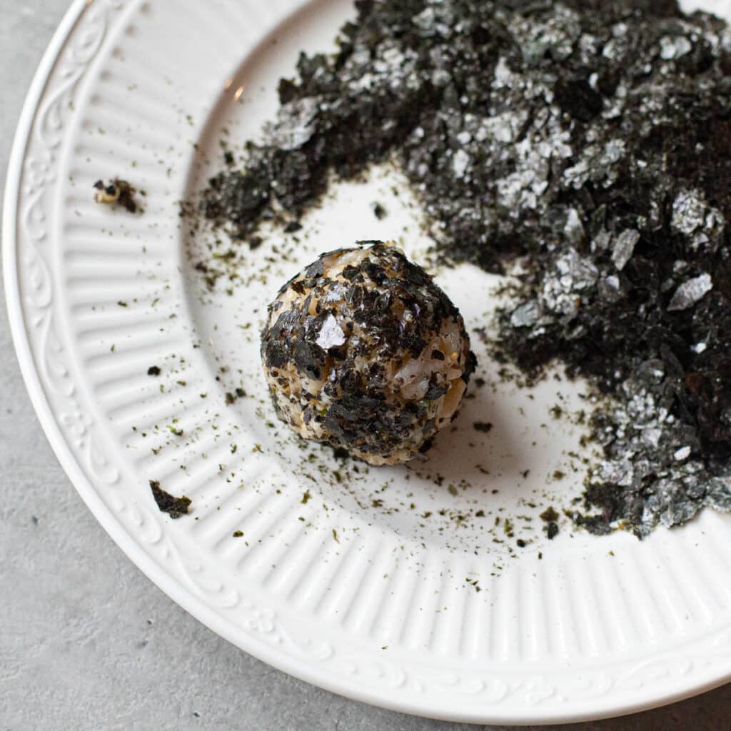 korean rice ball on a plate of crushed nori flakes