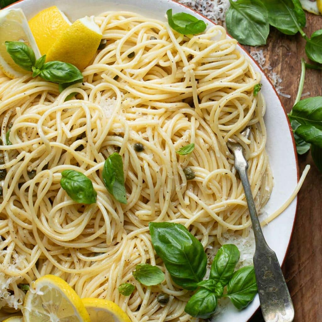 Lemon caper pasta in a white bowl with a silver fork