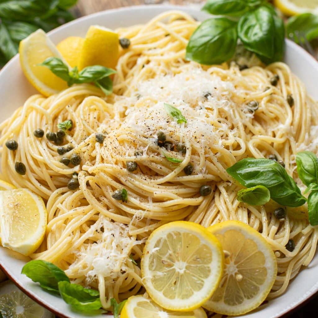 one pan lemon caper pasta with lemon slices and fresh basil leaves