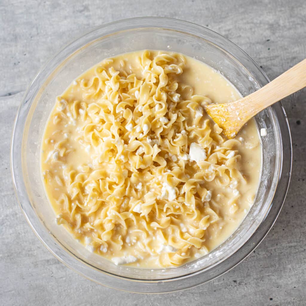egg noodles and custard mixed together in a glass bowl