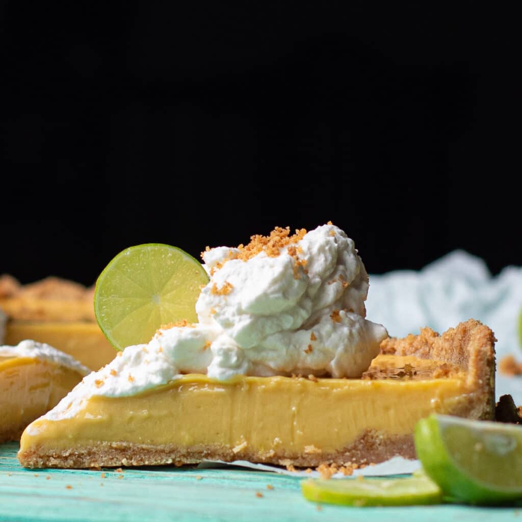 sideways view of a slice of key west key lime pie topped with whipped cream