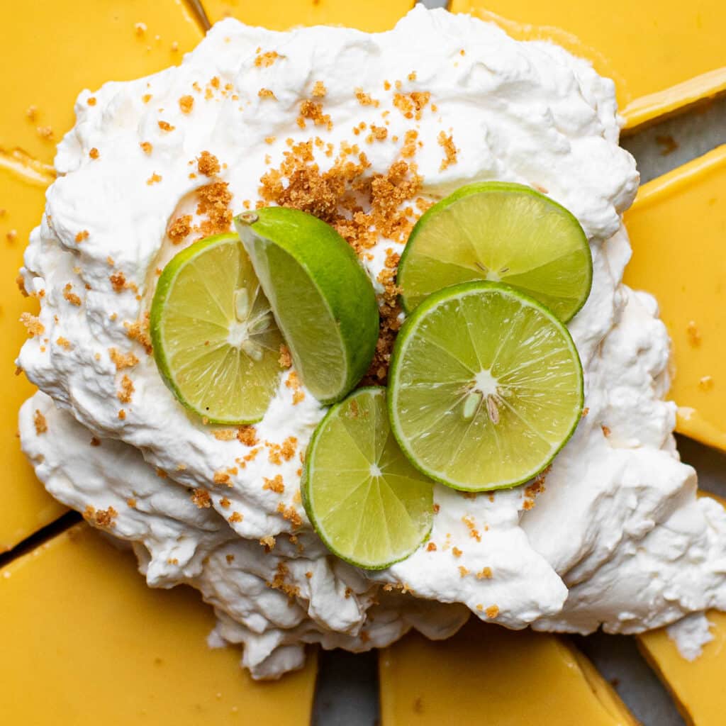 whipped cream topping with lime wedges and graham cracker crumbs