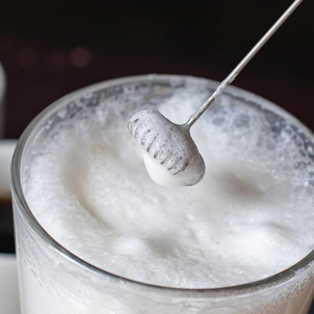 handheld milk frother with frothed milk on it 
