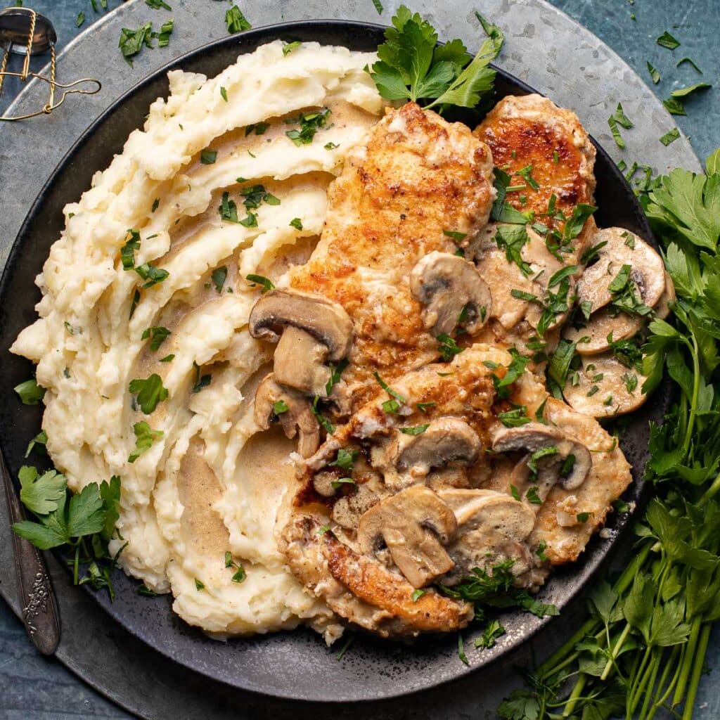 Champagne chicken with whipped potatoes on a black plate