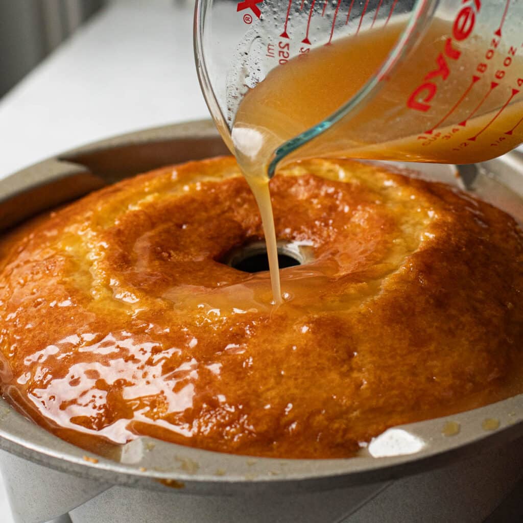 caramel sauce being poured over a butter cake