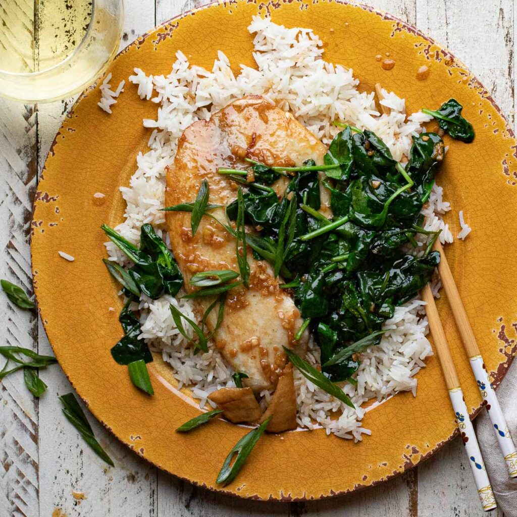 Asian tilapia with spinach and rice on an orange plate