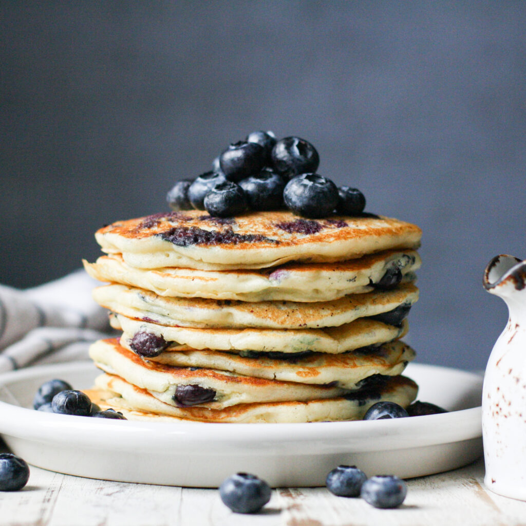 a stack of blueberry pancakes on a white plate