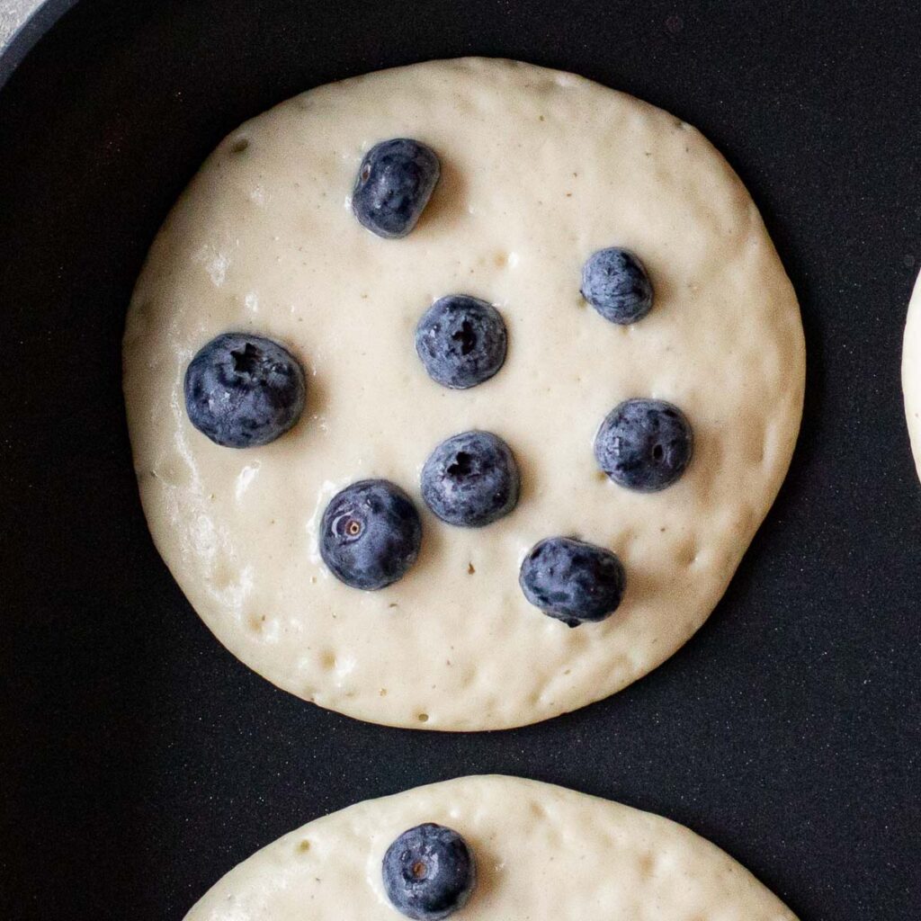 blueberry buttermilk pancakes cooking on a griddle