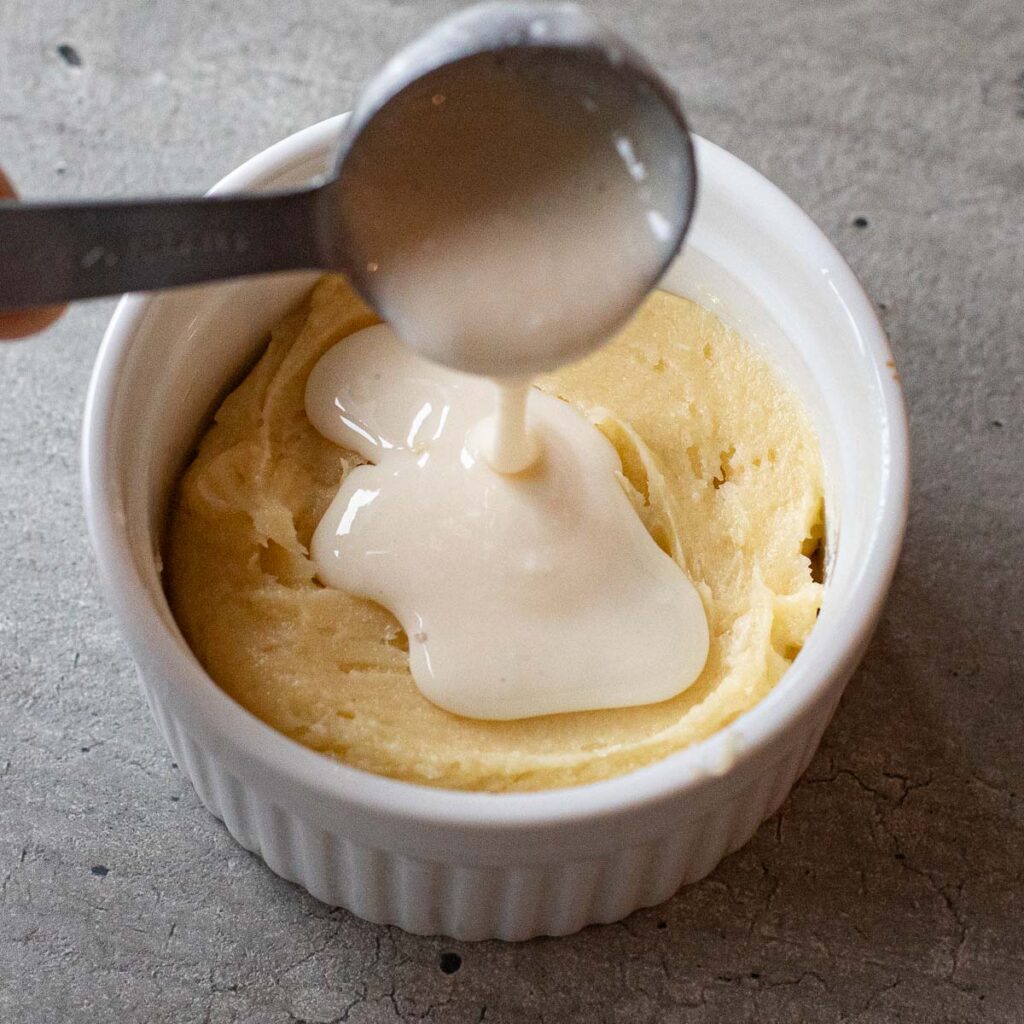the cheesecake layer of cpk butter cake being poured into a white ramekin