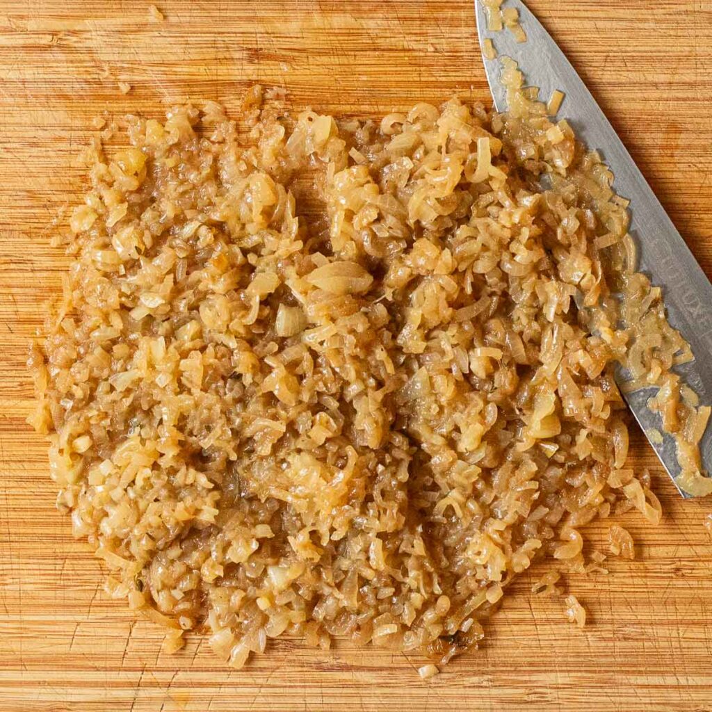 caramelized onions being chopped on a wooden cutting board