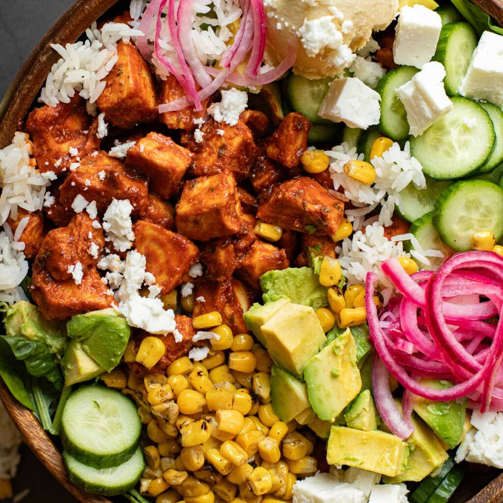 harissa chicken bowl with feta cheese, avocado, rice and pickled onions