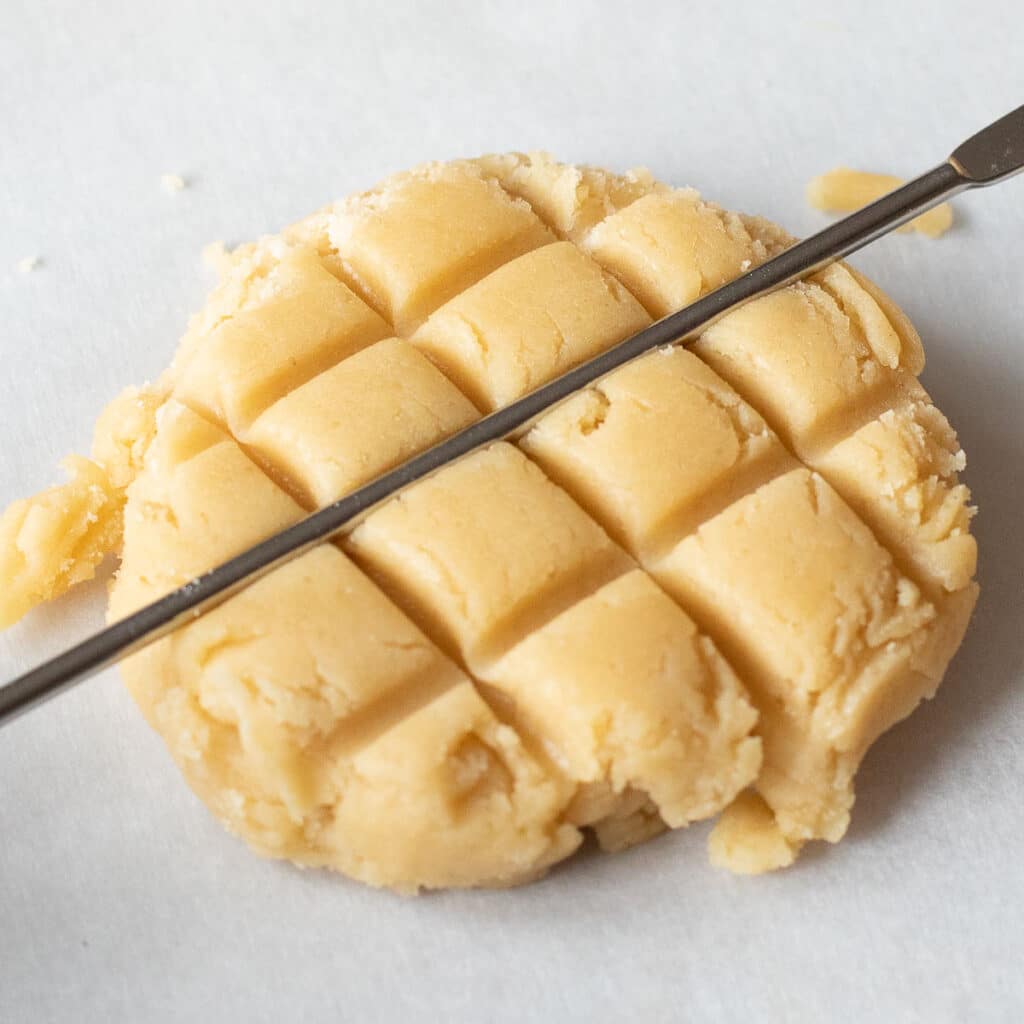 a metal skewer creating a waffle pattern in a cookie